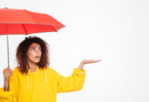 Black woman in raincoat with red umbrella